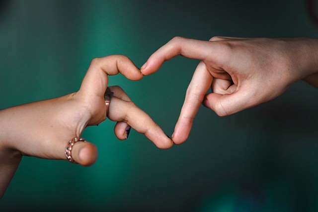 Kaksi kättä muodostavat sydänkuvion sormillaan.